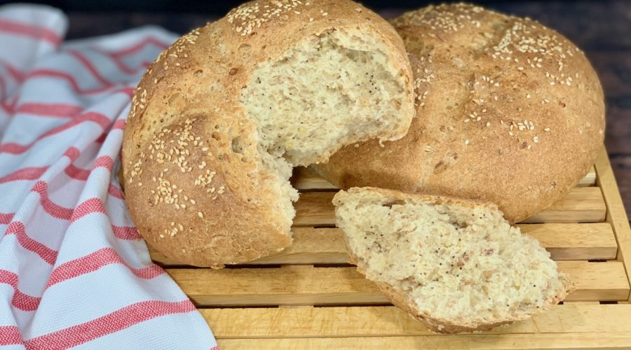 Closeup of Multigrain Sourdough Bread on cutting board with torn loaf and piece wide