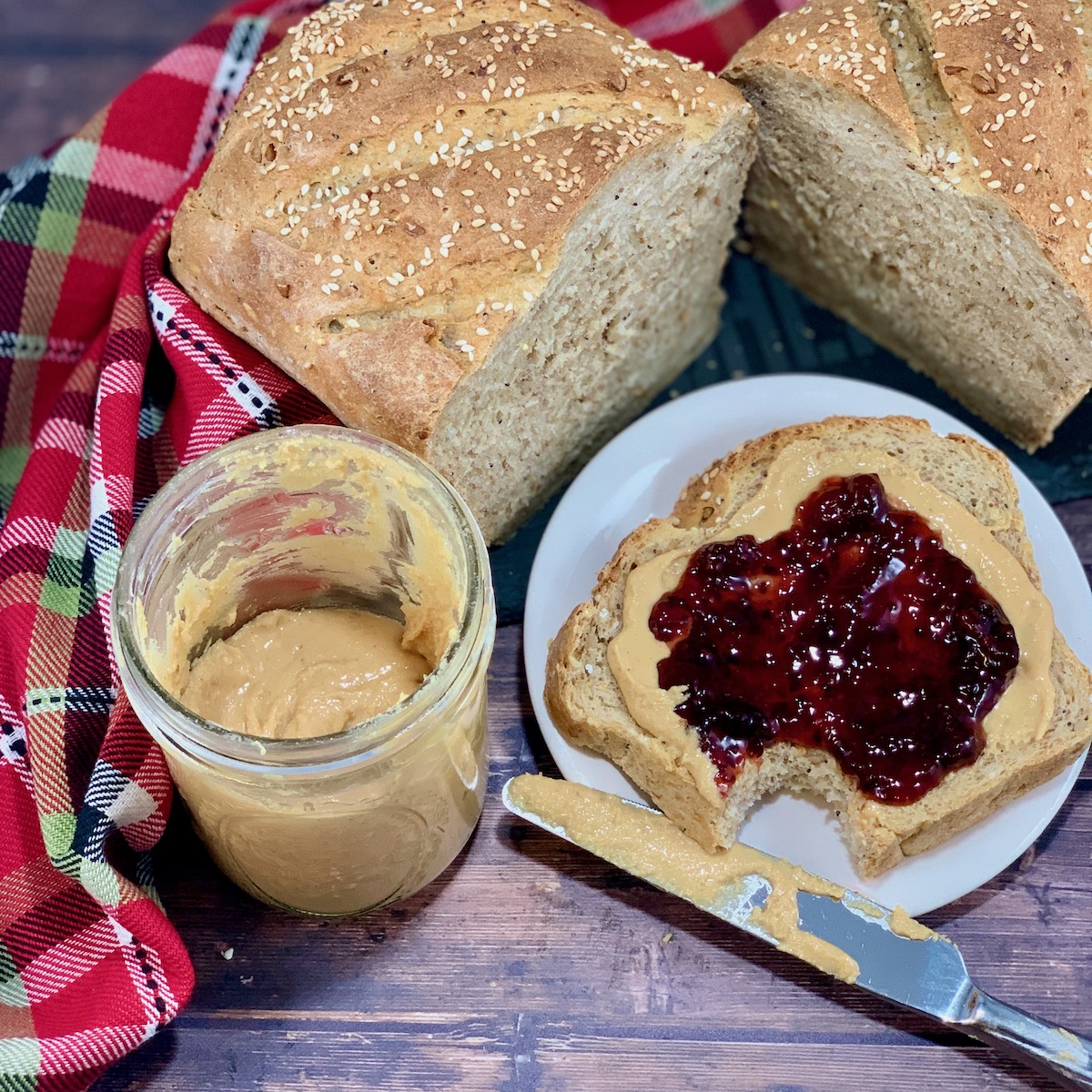 Open face peanut butter & jelly sandwich with bite and bread & jar