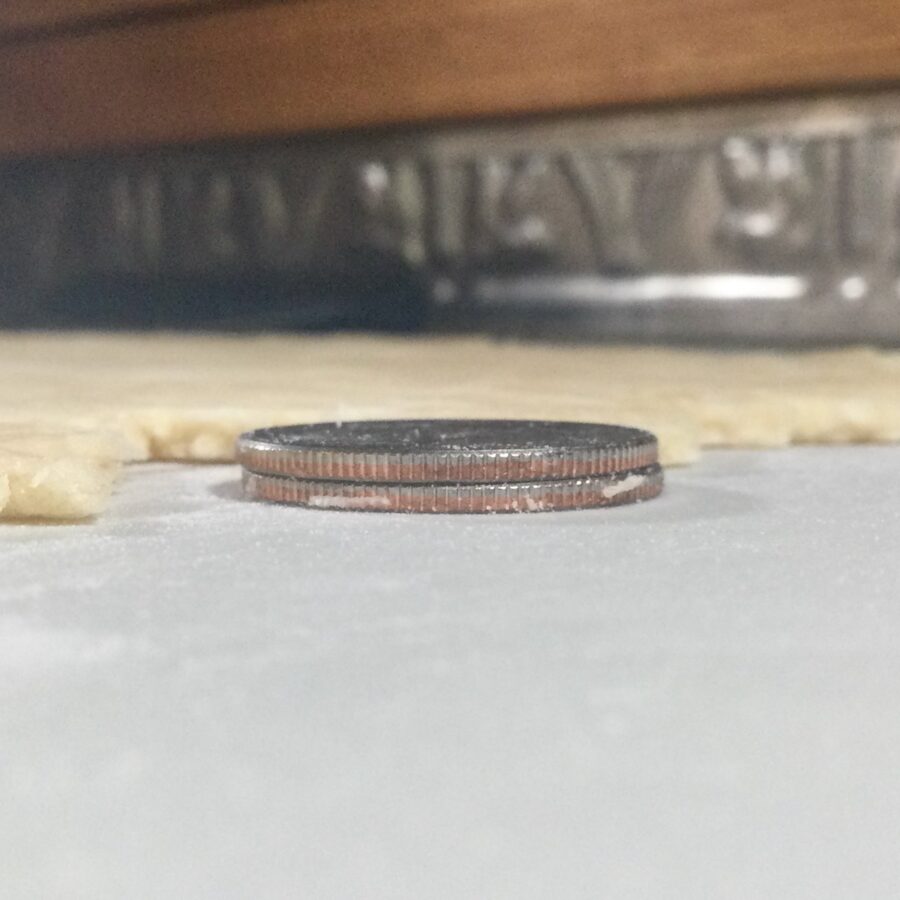 Measuring the height of Rolling out Sourdough Shortcrust Pastry dough with quarters closeup