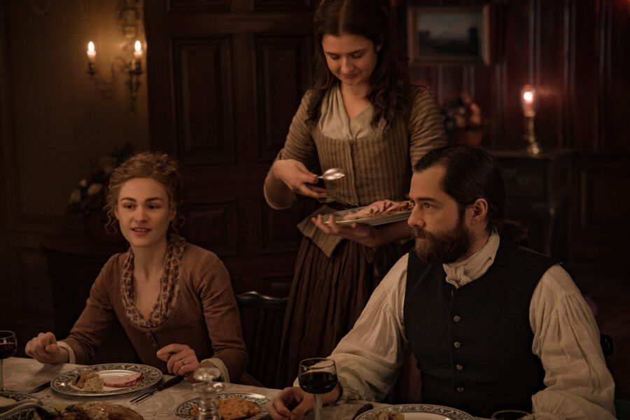 Bree and Roger at the dinner table with Lizzie serving.